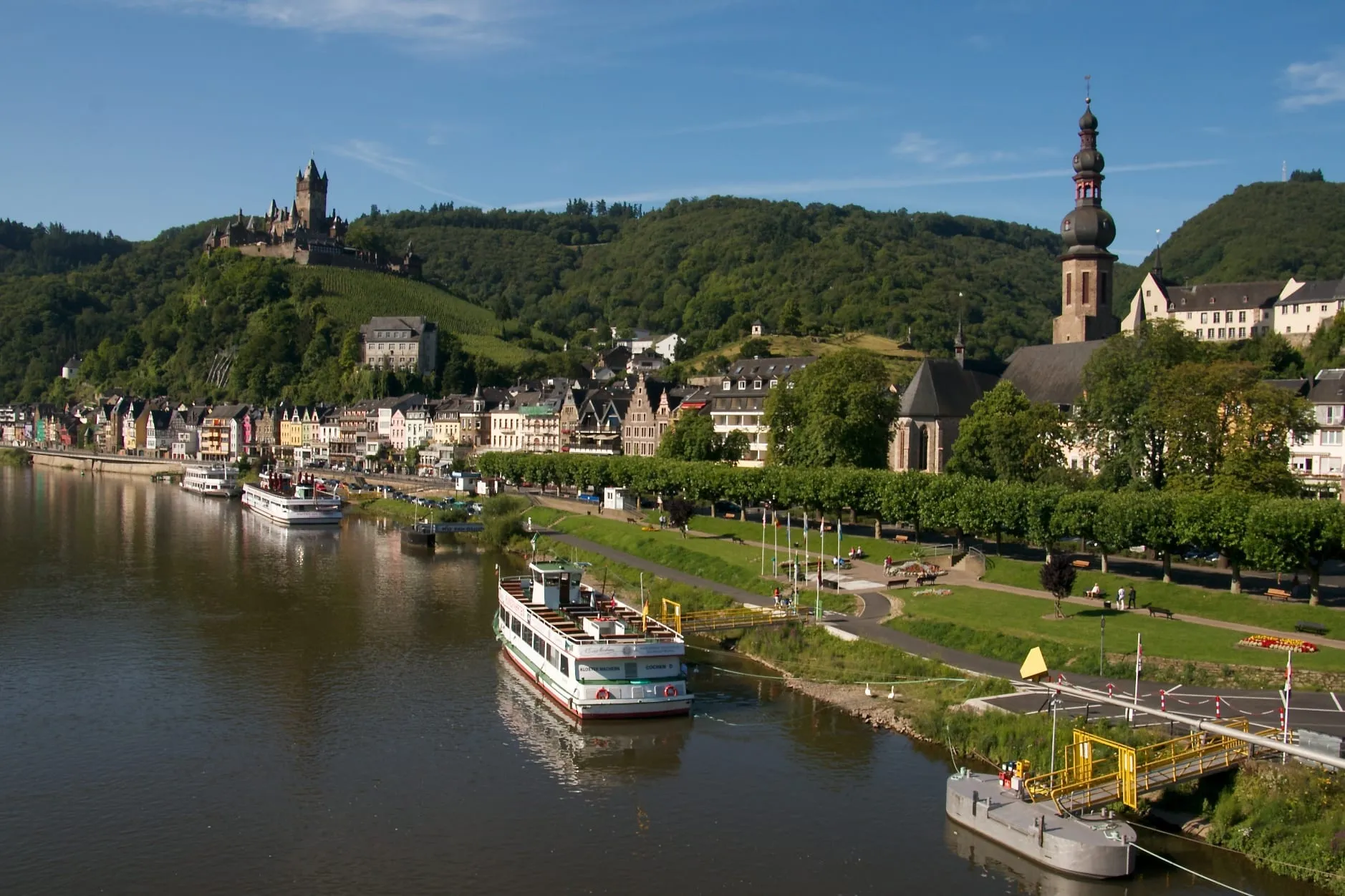 Moselpromenade in Cochem mit Ausflugsschiffen am Anleger, im Hintergrund die Reichsburg auf dem Burgberg