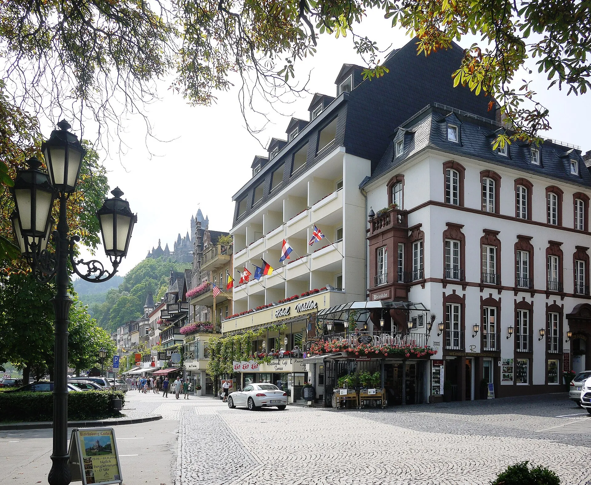 Hotel- und Restaurantzeile an der Moselpromenade in Cochem, dahinter die Reichsburg über den Dächern